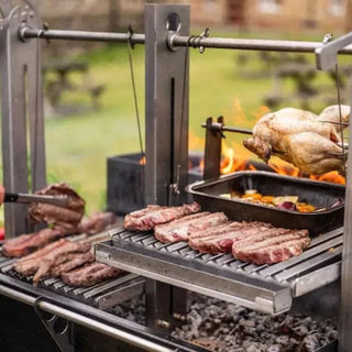 Outdoor grill with various meats and a chicken being cooked over an open flame.